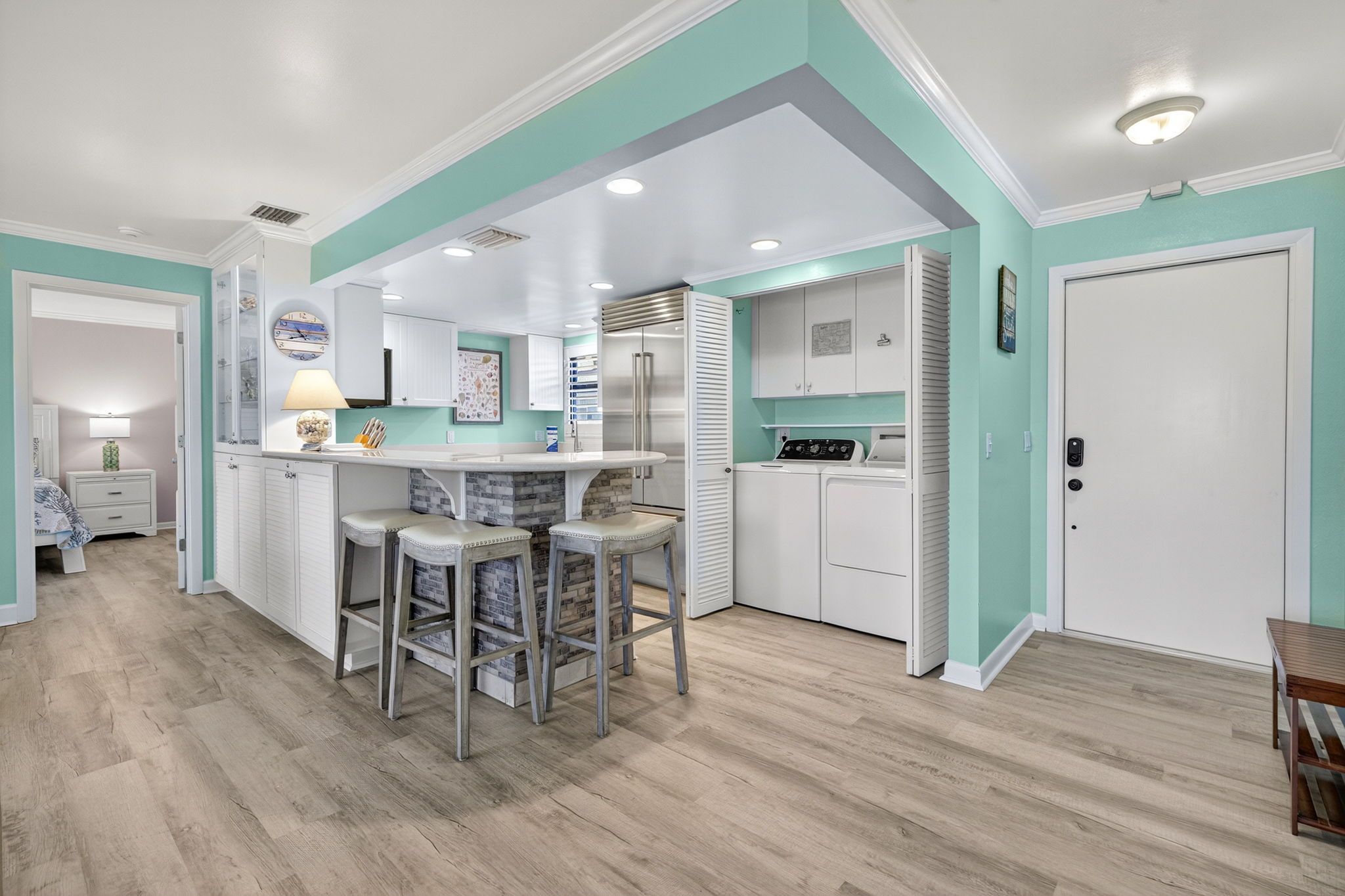 A modern kitchen with white cabinetry, a central island with bar stools, and a built-in oven.