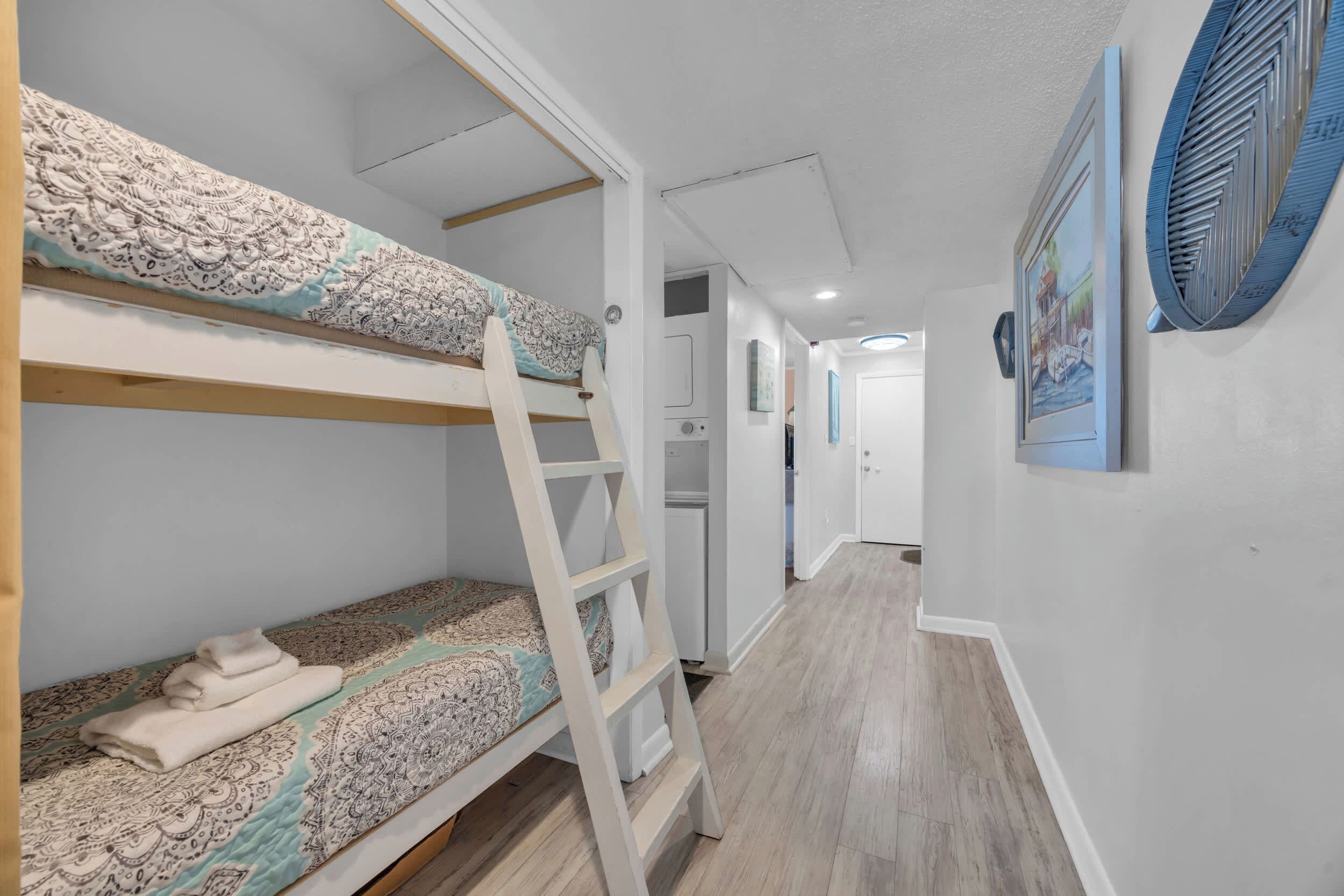 A bunk bed with a ladder, a folded blanket, and a patterned bedspread.