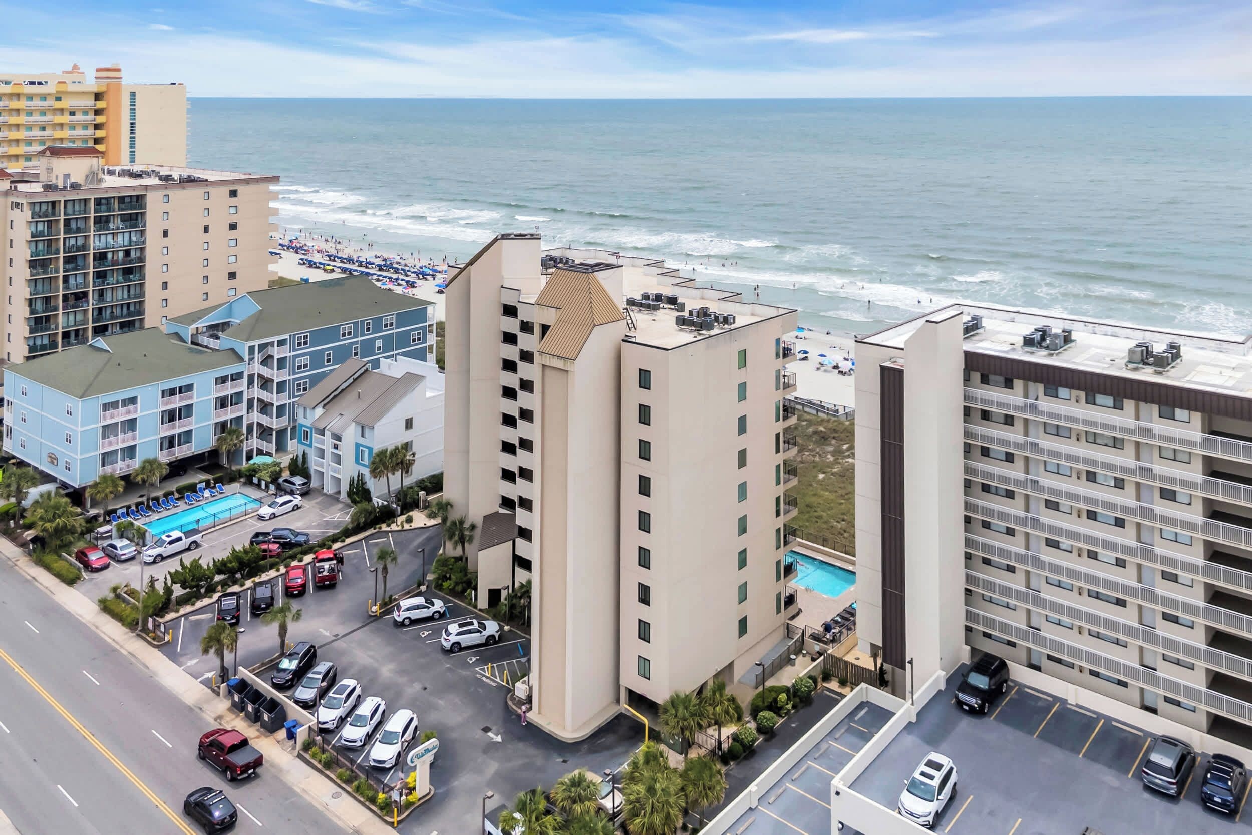A high-rise hotel with a rooftop pool, adjacent beach, and parking facilities.