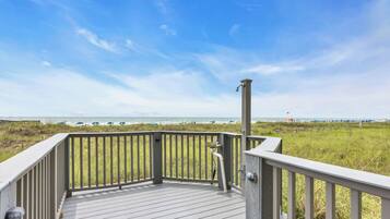 A wooden deck with a railing overlooking a beach.