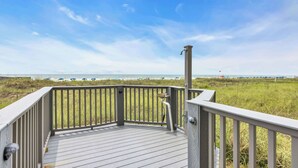 Eine Holzterrasse mit Geländer und Blick auf einen Strand.