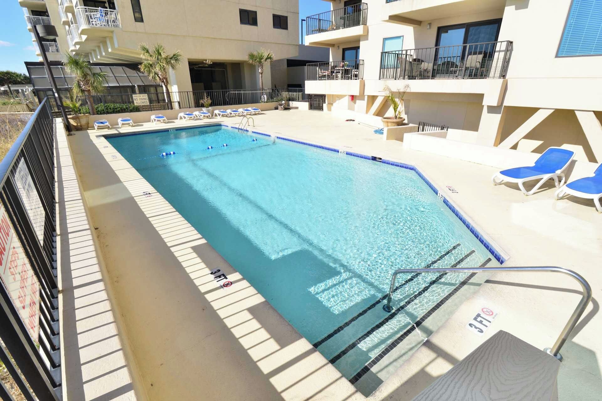 A swimming pool with lounge chairs and a lifeguard stand.