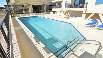 A swimming pool with lounge chairs and a lifeguard stand.
