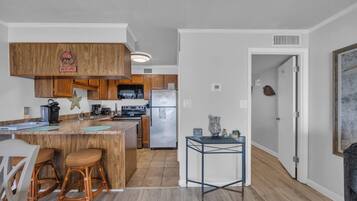 A modern kitchen with wooden cabinets, a stainless steel refrigerator, and a bar area with stools.