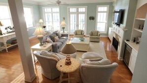 Amplia sala de estar con chimenea, televisor y comedor con mesa y sillas.