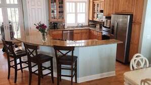 Una cocina con armarios de madera, un refrigerador de acero inoxidable y una isla grande con taburetes de bar.