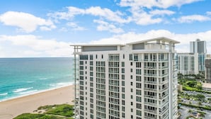 Un hôtel de grande hauteur, avec de nombreux étages, de grandes fenêtres et une vue sur la plage et l’océan.
