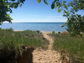 A sandy beach path leading to the sea, surrounded by grass and trees. - Good Hart Beach Cottage on 100' of Private Beach on Lake Michigan (Harbor Springs)