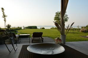 Un patio al aire libre con vista al mar, una silla de mimbre, una mesa y un cuenco decorativo.