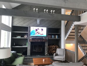 TV connectée, cheminée, livres, chaîne hi-fi