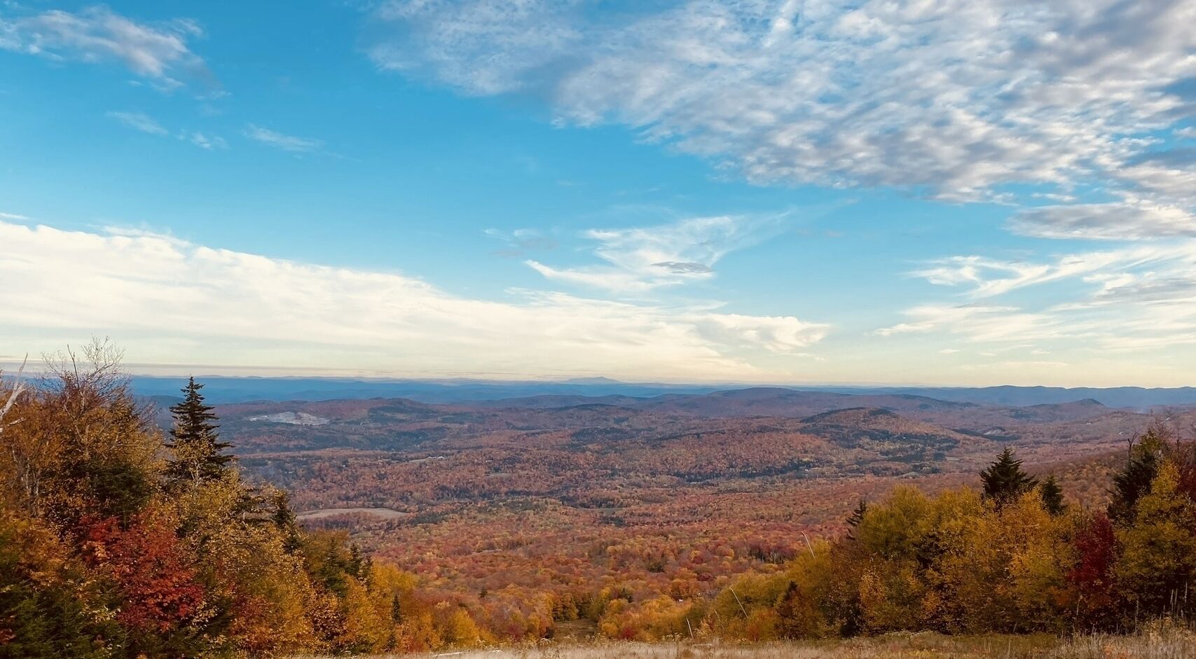 Panorama su un paesaggio montuoso con autunno, cieli sereni e colline lontane.