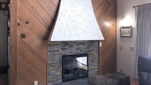 A fireplace with a stone base and a wooden backdrop.