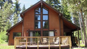 A wooden cabin with a large front porch and multiple windows.