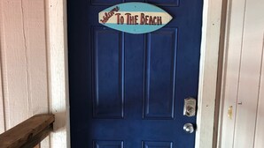A blue door with a 'Welcome To The Beach' sign above it.