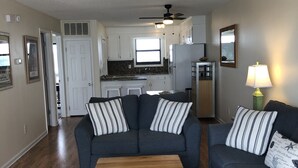 A living room with two sofas, a coffee table, and a kitchen in the background.