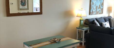 A dining area with a wooden table and benches, a ceiling fan, a lamp, and a couch.