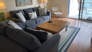 A living room with a grey sofa, a wooden coffee table, and a striped rug.