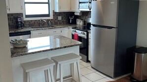 A modern kitchen with white cabinets, a stainless steel refrigerator, a microwave, and a coffee maker.