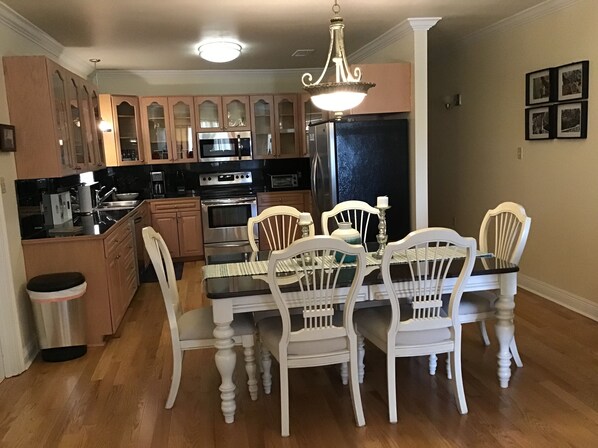 A kitchen with wooden cabinets, a refrigerator, a stove, and a dining table with chairs.