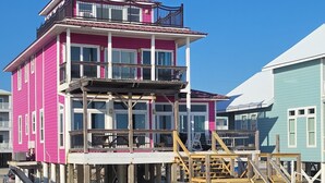 Un edificio de varios pisos con un balcón en el nivel superior, ubicado en una playa de arena.