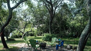 Un'area esterna con posti a sedere, pavimento in pietra, poltrone Adirondack verdi e un tavolino.