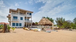 Ein Strandhotel mit Pool, einer Struktur mit Reetdach und mehreren Balkonen.