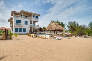 Un hôtel situé en bord de mer, doté de nombreux balcons, d’une piscine et d’une structure dont le toit est fait de chaume.