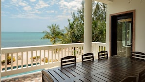 Ein Balkon mit Blick auf das Meer, ein Holztisch und Stühle.