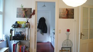 Un couloir avec une bibliothèque, un porte-manteau et une porte donnant sur une autre pièce.