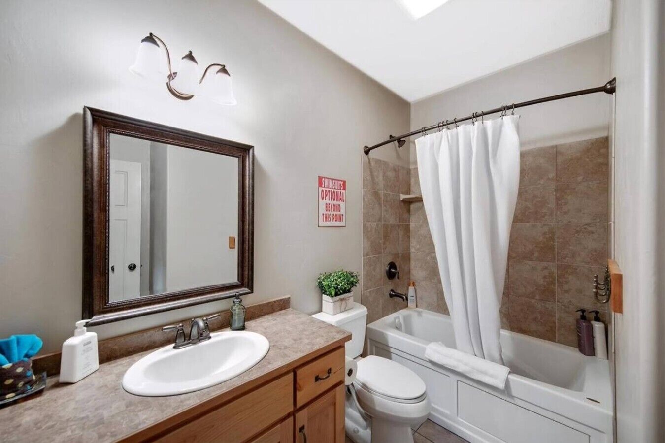 Un baño con lavamanos, espejo, inodoro y ducha.