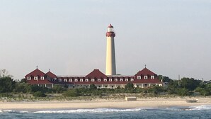 Un edificio costero con un faro, que presenta una fachada simétrica con varias ventanas y una torre central.