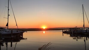 Un puerto deportivo al atardecer con barcos amarrados y agua tranquila que refleja el cielo.