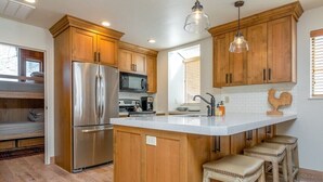 Una cocina moderna con armarios de madera, electrodomésticos de acero inoxidable y una isla grande con taburetes de bar.