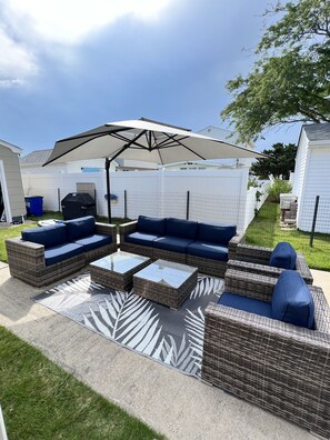 A patio area with outdoor furniture, including sofas and a table, under a large umbrella. - Bay La Vie Bungalow: Cozy, Pool, Beach, Sunsets (Villas)