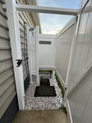 A small outdoor area with a white gate, a metal bench, and a black mat. - Bay La Vie Bungalow: Cozy, Pool, Beach, Sunsets (Villas)