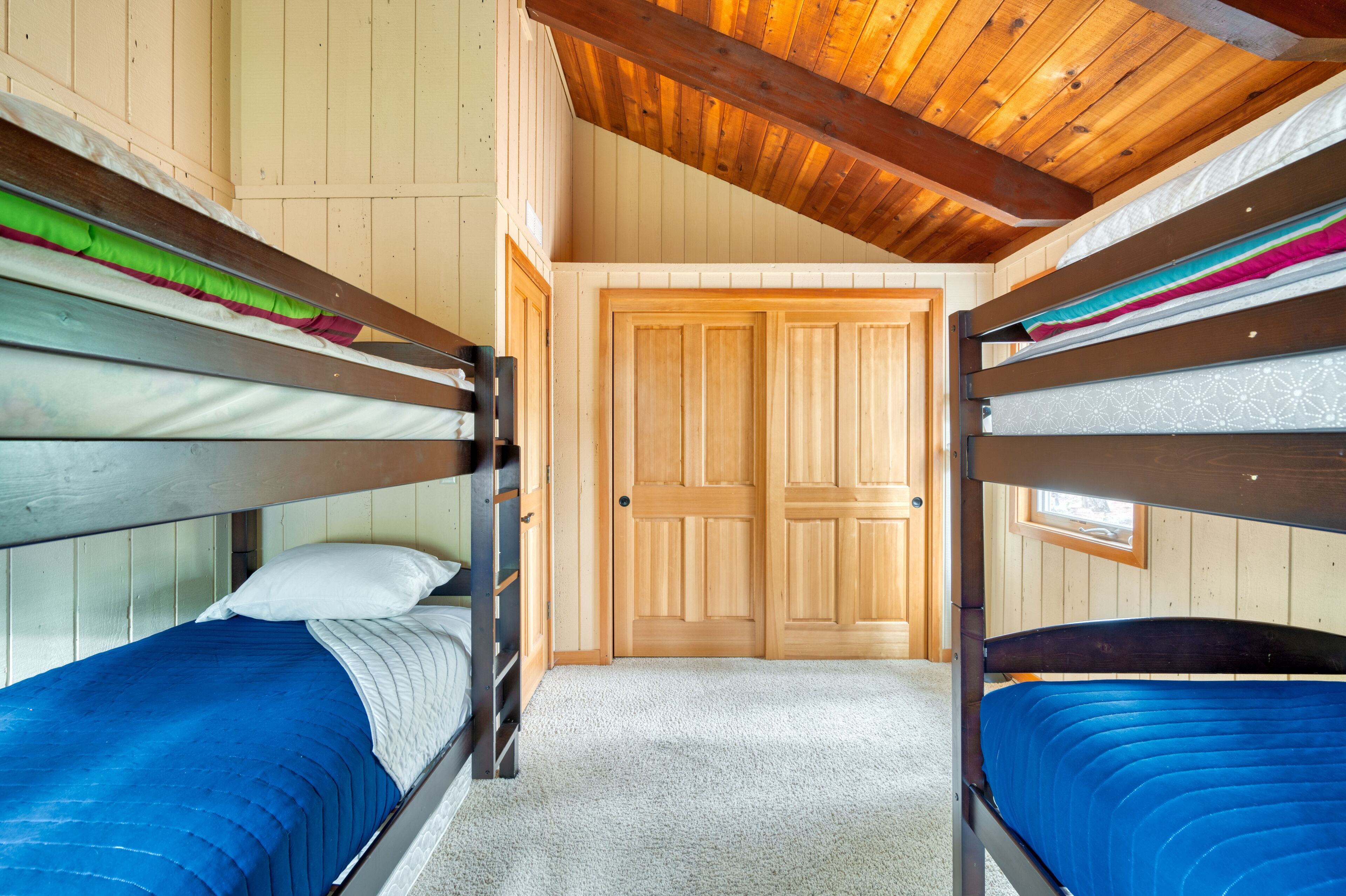 A bunk bed room with wooden walls and a wooden ceiling.