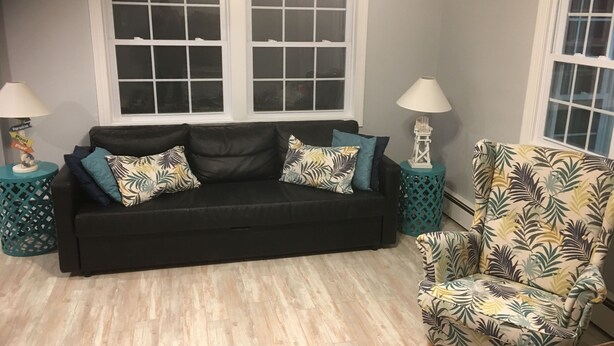 A living room with a black sofa, patterned armchair, and two side tables with lamps. - Cape May Family Friendly Home Near Beach and Mall (Cape May)