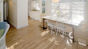 A bright, open-plan kitchen and dining area with white cabinetry and a wooden floor. - In-Town • Walk to Beaches • Charming Cottage • Private Patio & Easy Parking (Nantucket)