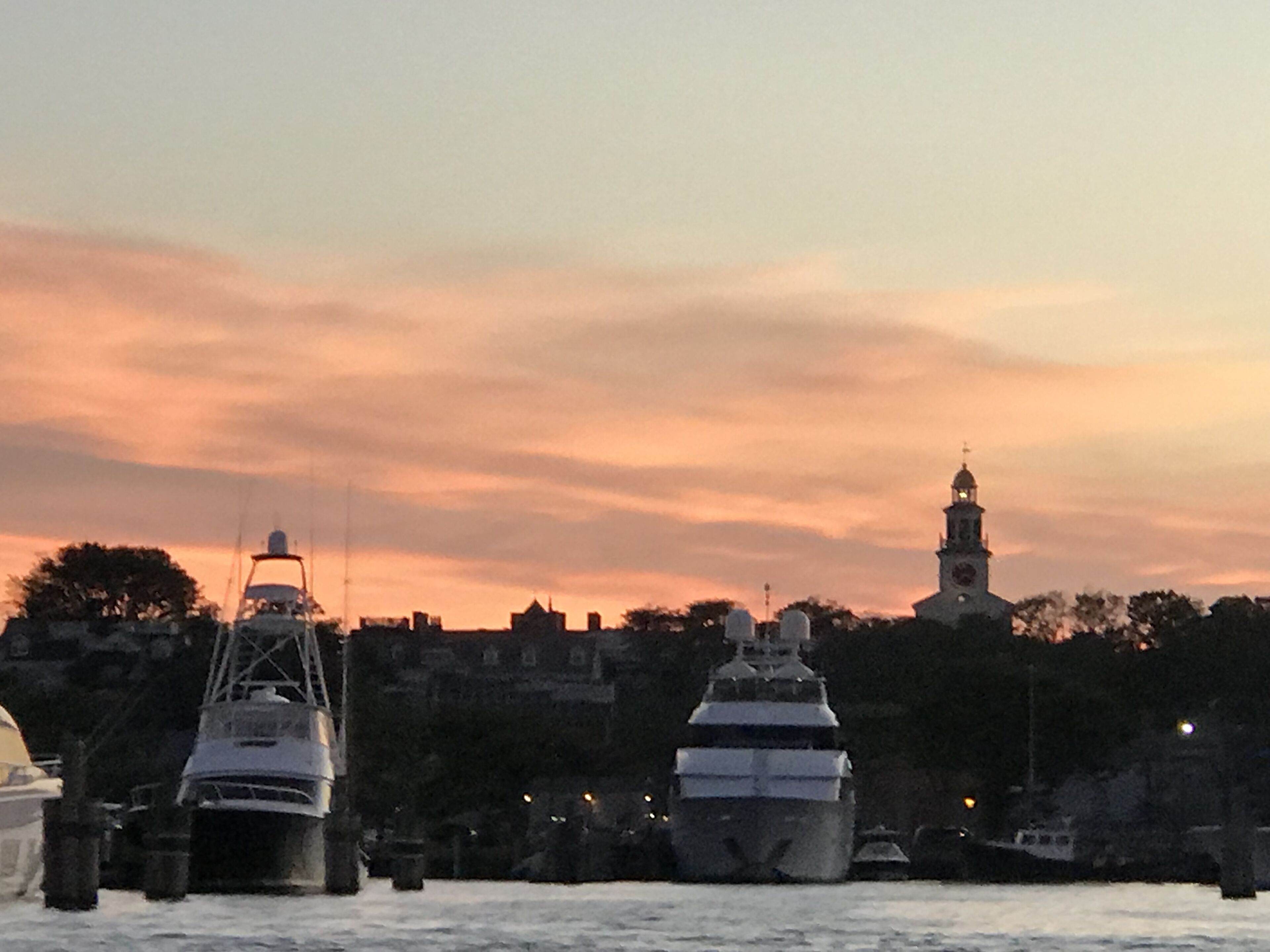 A harbor with boats and a tower in the background during sunset.