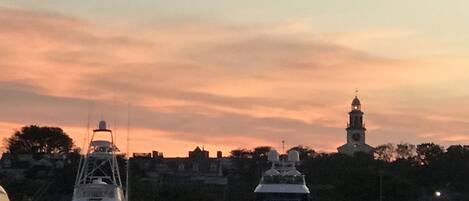 A harbor with boats and a tower in the background during sunset.