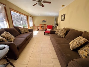 A living room with two sofas, a dining table, and a ceiling fan.