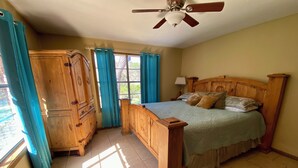 A bedroom with a wooden bed, a wardrobe, a ceiling fan, and a window with curtains. - STUNNING Private Frio River! Ping Pong, Guest Cabin, Rope Swing, Kayak Heaven (Leakey)