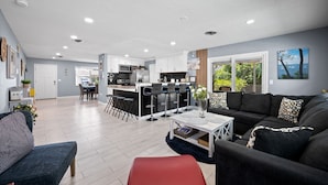 A modern kitchen with a central island, bar stools, and a dining area with a table and chairs. - BEAUTIFUL HOME WITH HEATED POOL!!! (Venice)