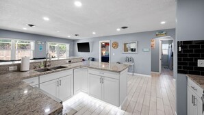 A modern kitchen with white cabinets, granite countertops, and a large island. - BEAUTIFUL HOME WITH HEATED POOL!!! (Venice)