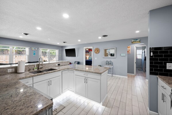 A modern kitchen with white cabinets, granite countertops, and a large island.