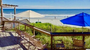 A beachside patio with outdoor seating and umbrellas, overlooking the ocean. - Royale Palms 14022H Oceanview Studio in Kingston (Myrtle Beach)