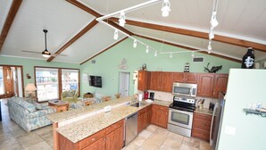 A spacious kitchen with wooden cabinets, a granite countertop, and stainless steel appliances. - Summer Sale! Steps to Beach, Amazing View! Pool, Game room, Hot-tub! (St George Island)