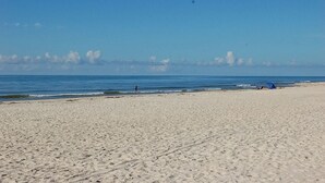 A wide sandy beach with a clear sky and calm sea. - Summer Sale! Steps to Beach, Amazing View! Pool, Game room, Hot-tub! (St George Island)