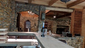Un espace bar aux murs de pierre, avec un évier, des verres et une bouteille de vin.