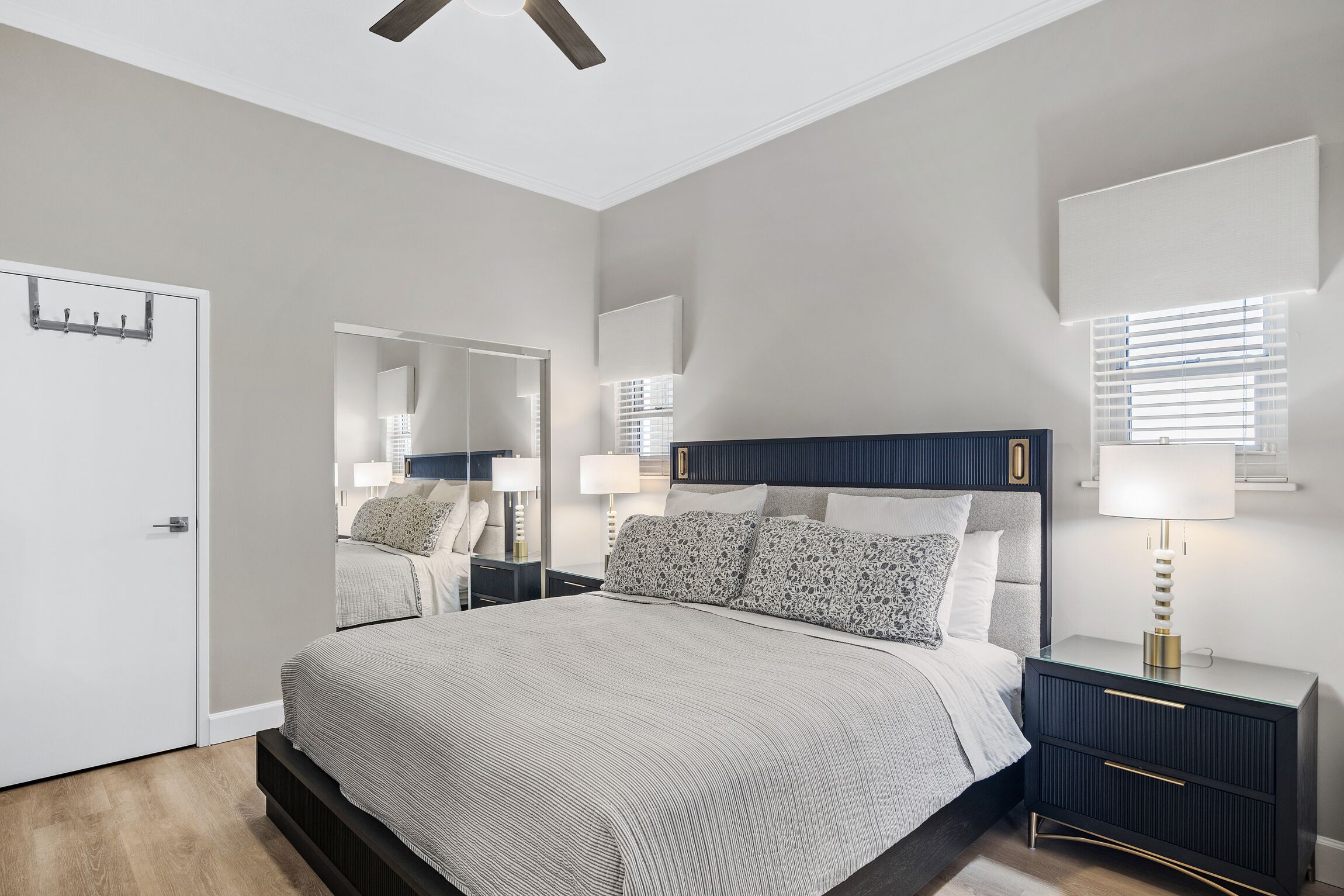 Une chambre moderne avec un grand lit, des tables de chevet, un miroir et un ventilateur de plafond.